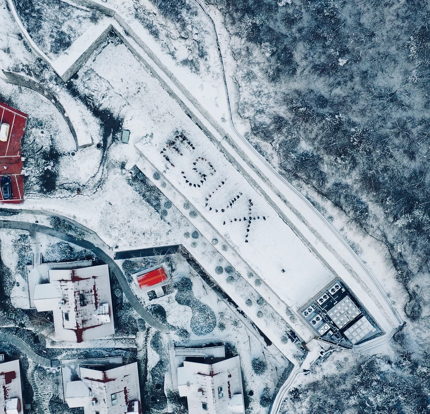 Aerial view of a snow-covered campus lane with the team lying in the snow
